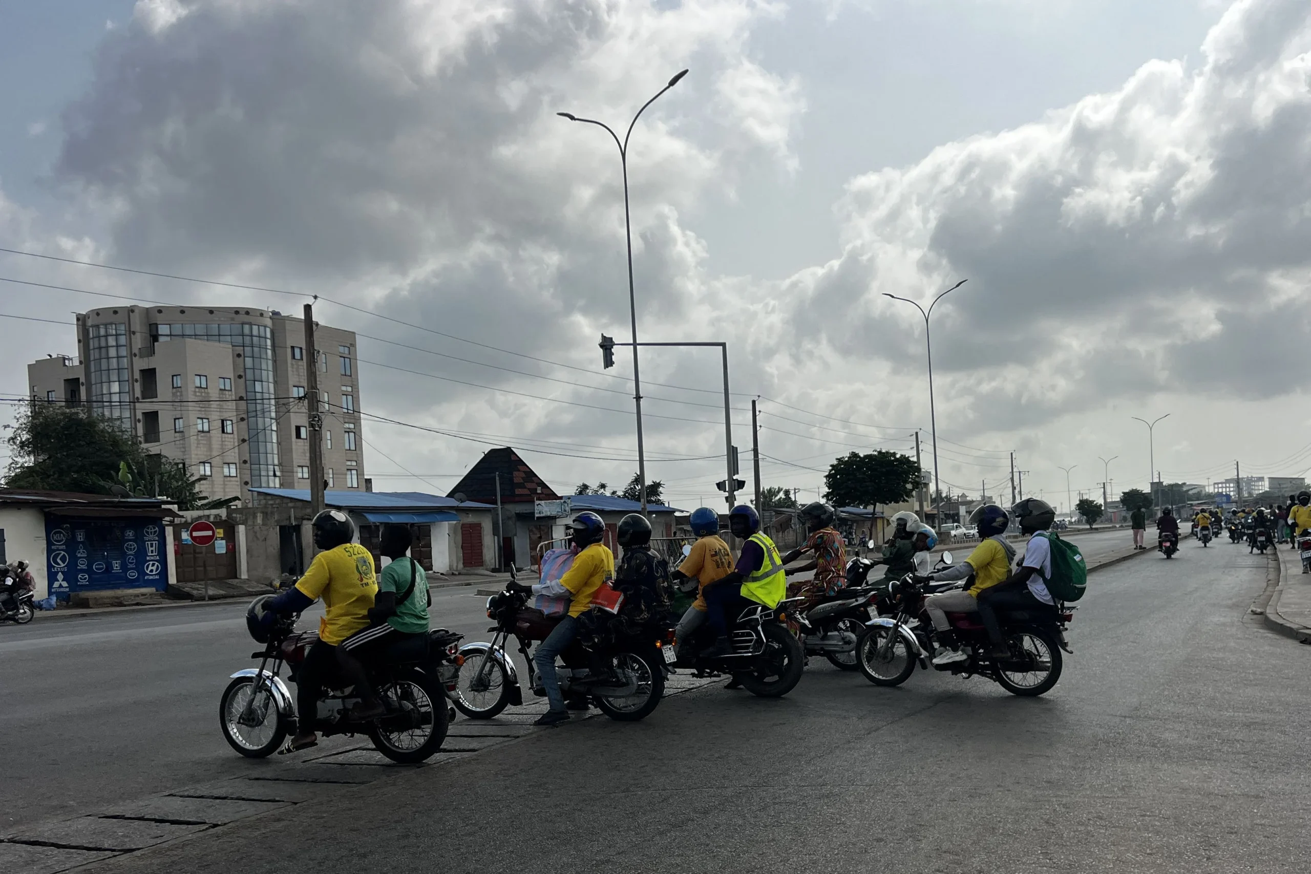 Motorcycle taxis ferrying passengers at a Cotonou intersection during rumors of a potential coup d’état in Benin