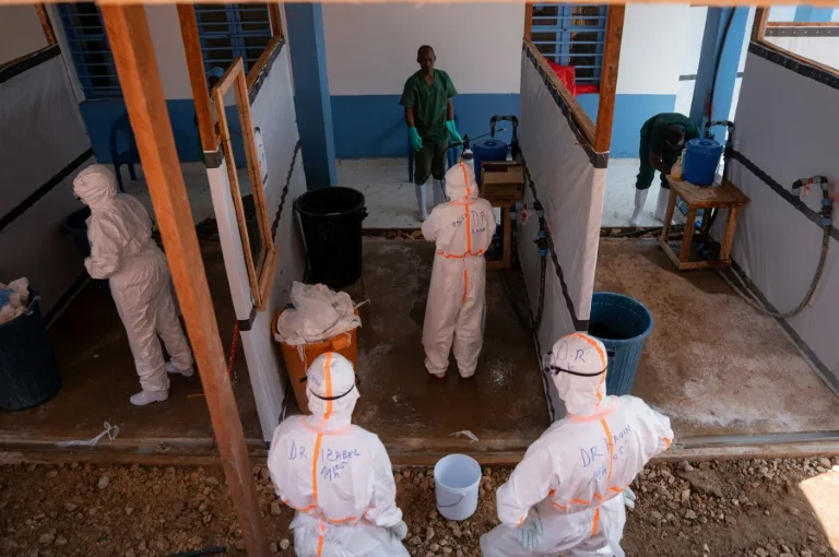 Healthcare workers in protective gear attending to Ebola patients in a Congolese treatment center